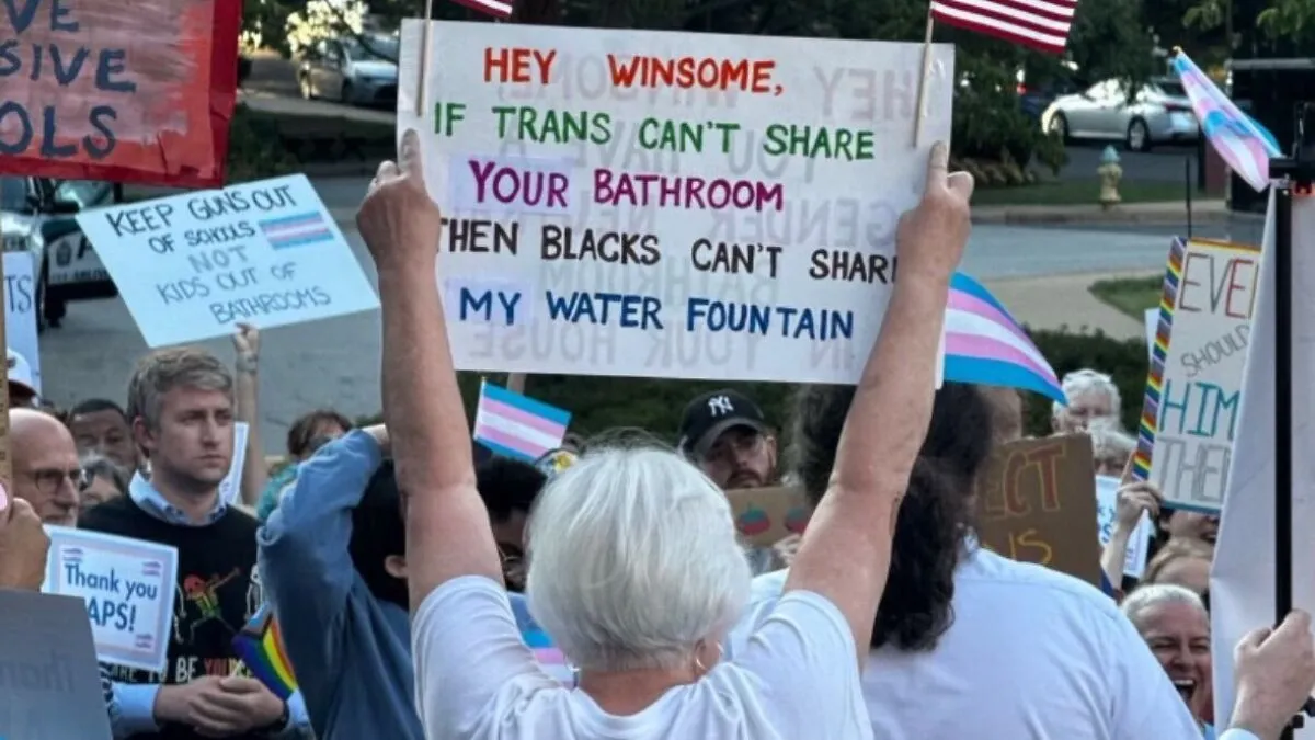 Outrage As Trans Rights Protester Waves Racist ‘Blacks Can’t Share My Water Fountain’ Sign